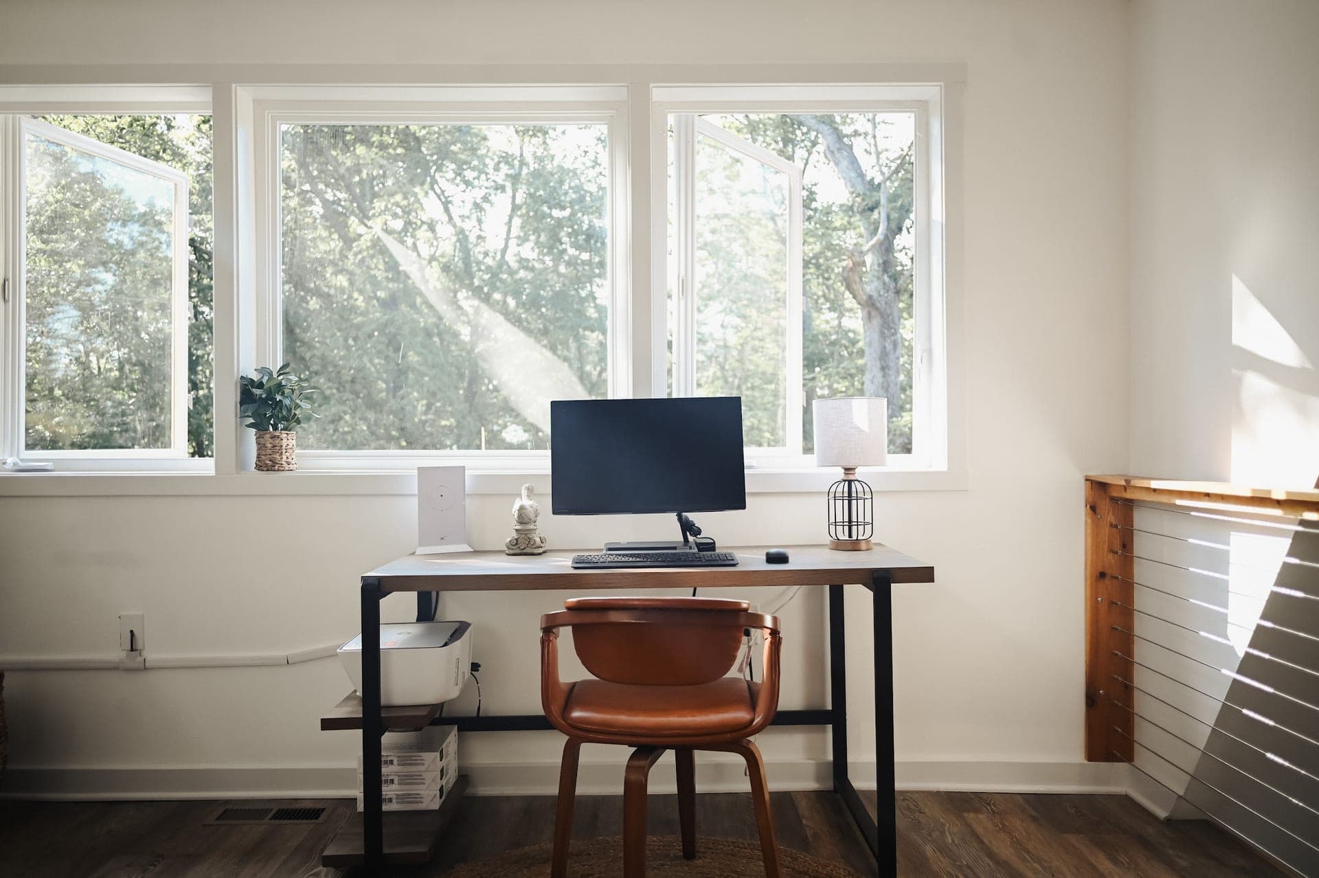 The workspace: desk, monitor and printer, with windows into the trees