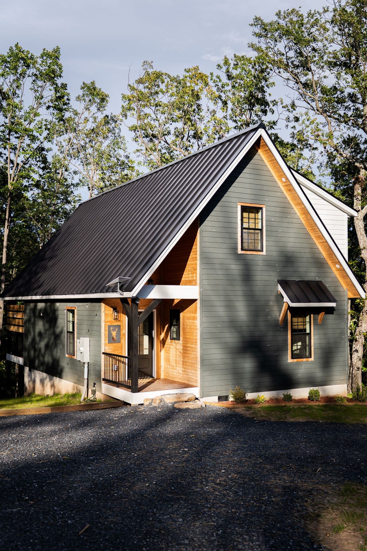 The Stag by day from the gravel drive, its steep metal roof rising into the trees