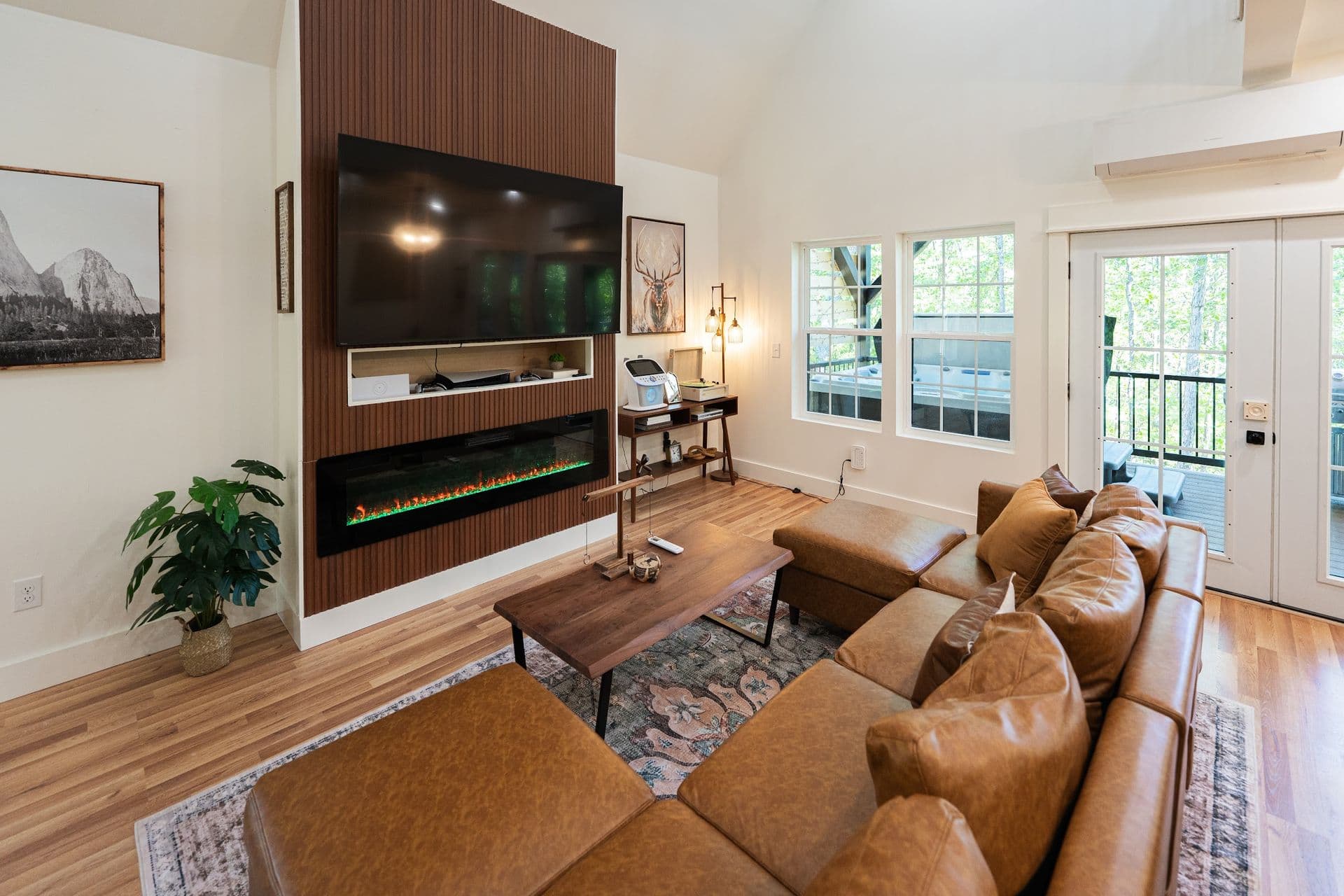 The great room: a leather sectional facing the 75-inch TV and electric fireplace on a slatted wood wall
