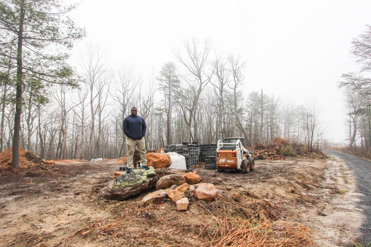 Morry on the build site — raw land before the first cabin