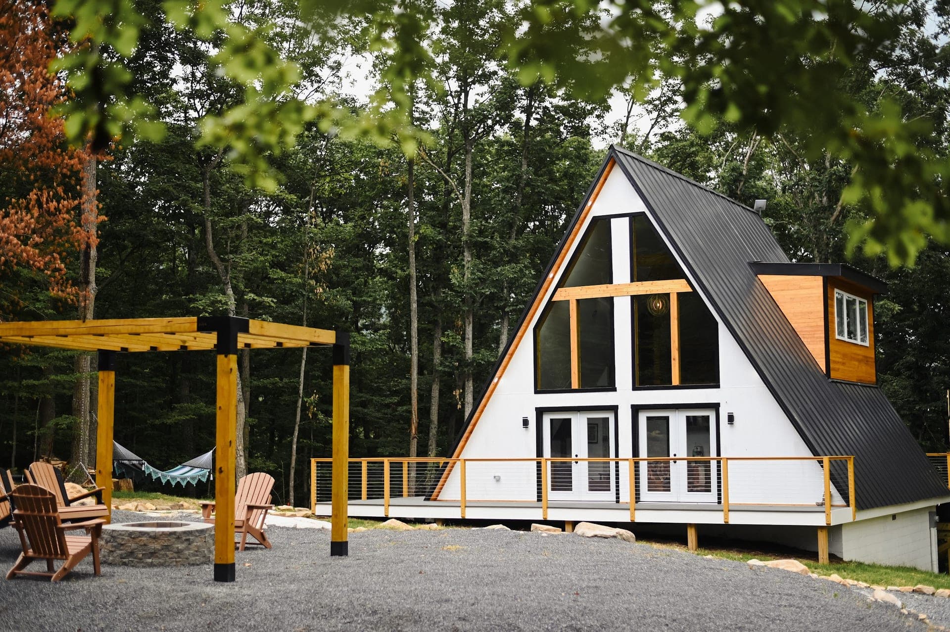 The Sparrow A-frame beside its pergola, fire pit and hammock in the Blue Ridge forest